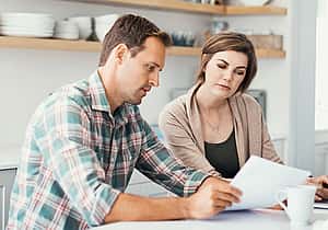 Young couple at home reviewing a tax invoice and discussing VAT regulations, Direct Debit, lease payments, and financial document reading.
