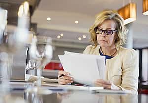 A businesswoman focused on reviewing a VAT Schedule document at table. Importance of document retention, agreement details, financial management.
