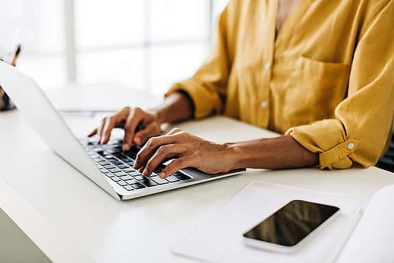 An older businessman leaning and using his laptop, focused on utilising grenke's Partner Portal to streamline financing processes, calculate quotes, and submit proposals for quick responses.
