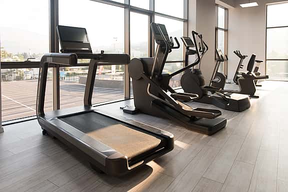 Assortment of treadmills, ellipticals, and exercise machines in a gym setting, showcasing grenke's financing options for fitness equipment, from cross-trainers to full gym refits.