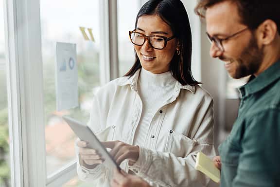 A couple looking at a printed document, discussing the simplicity of grenke's eSignature feature and its time-saving benefits, eliminating the need for in-person meetings.