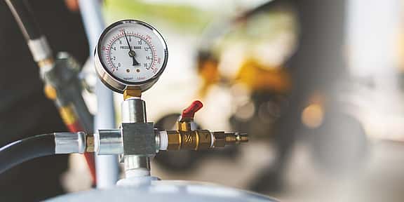 Close-up of an air compressor dial, highlighting grenke's financing solutions for compressors used in various applications, including construction sites, workshops, and cleaning purposes.