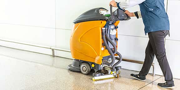 Person operating a large cleaning machine in a commercial environment, showcasing grenke's financing solutions for industrial vacuums, floor scrubbers, and high-quality cleaning equipment.