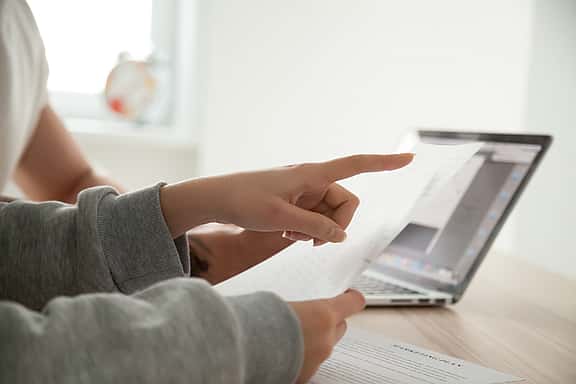 Close-up of female hand pointing to document with important instructions.