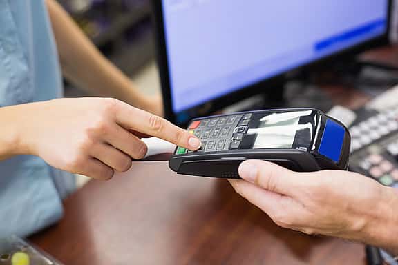 Close-up of hands pressing a button on a card reader, highlighting grenke's financing options for retail and point of sale equipment, including cash register computers, control panels, scanners, receipt printers, and cash drawers.