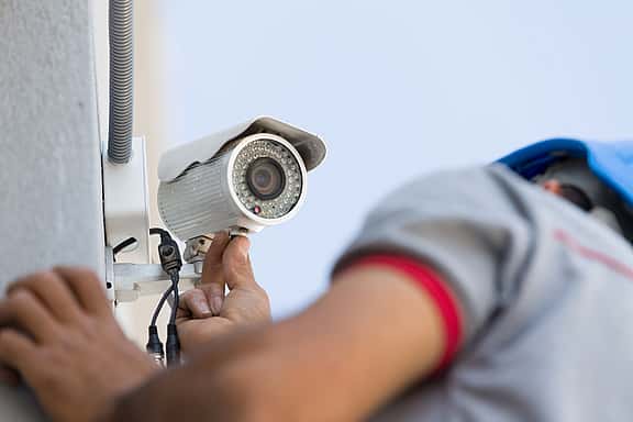 Close-up of hands setting up a CCTV camera in an office environment, illustrating grenke's financing options for security systems, alarm systems, and surveillance cameras to protect valuable equipment.