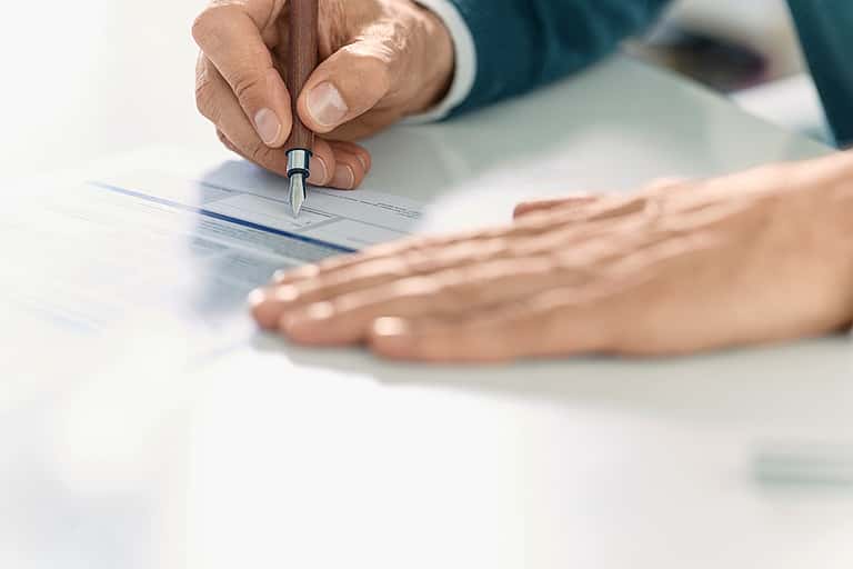Close-up of hands signing a document, emphasising the importance of inspecting equipment before signing the Delivery Certificate to confirm the lease agreement.