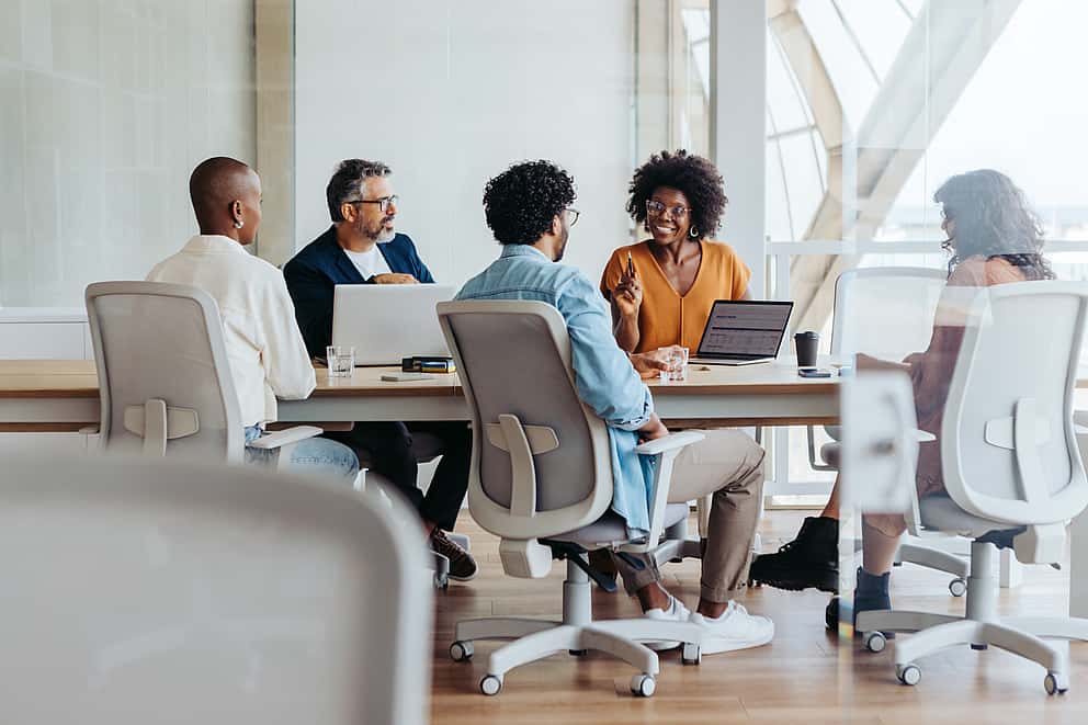 Three business people in a meeting room engaged in a project, symbolising grenke's role in powering growth through leasing solutions, supporting businesses to adapt and secure customer ambitions in today's operating environment.